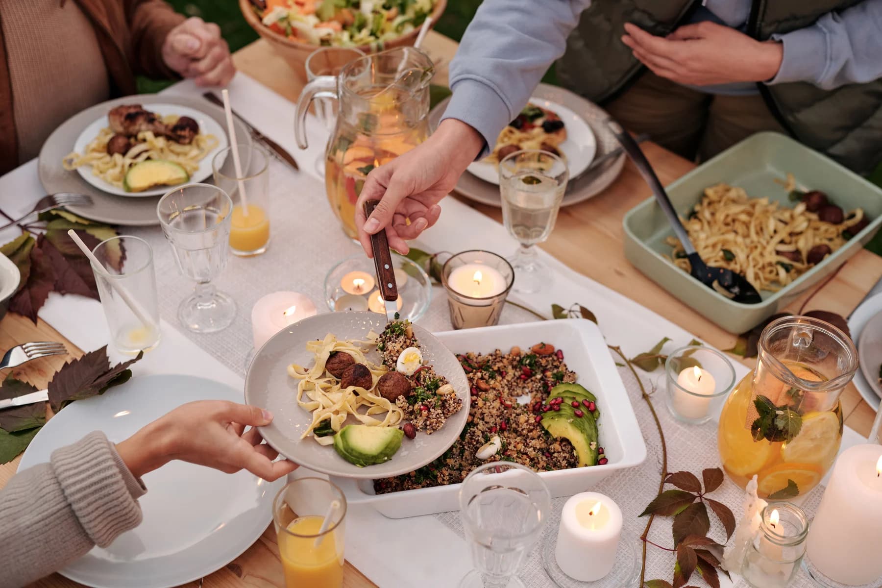Friends passing dishes around a candlelit dinner table
