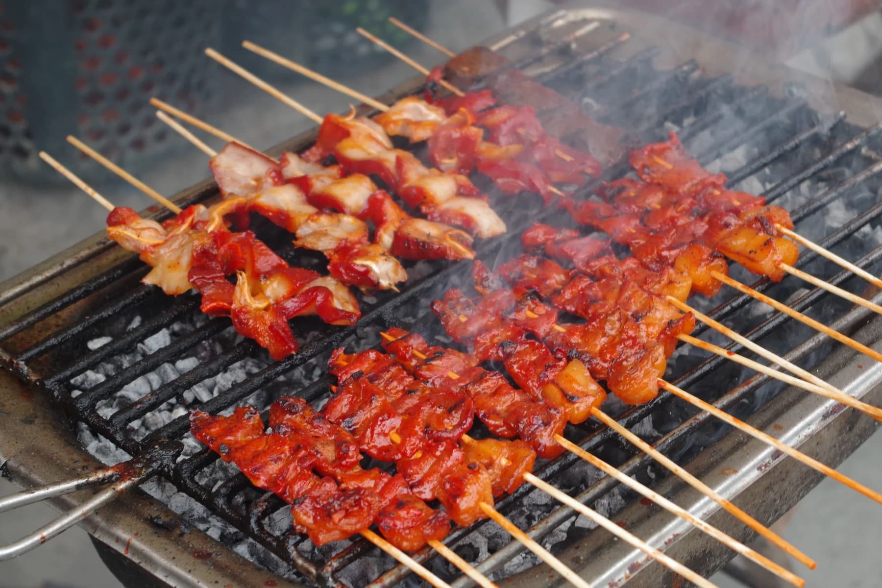 Chicken skewers cooking over a smoky charcoal grill