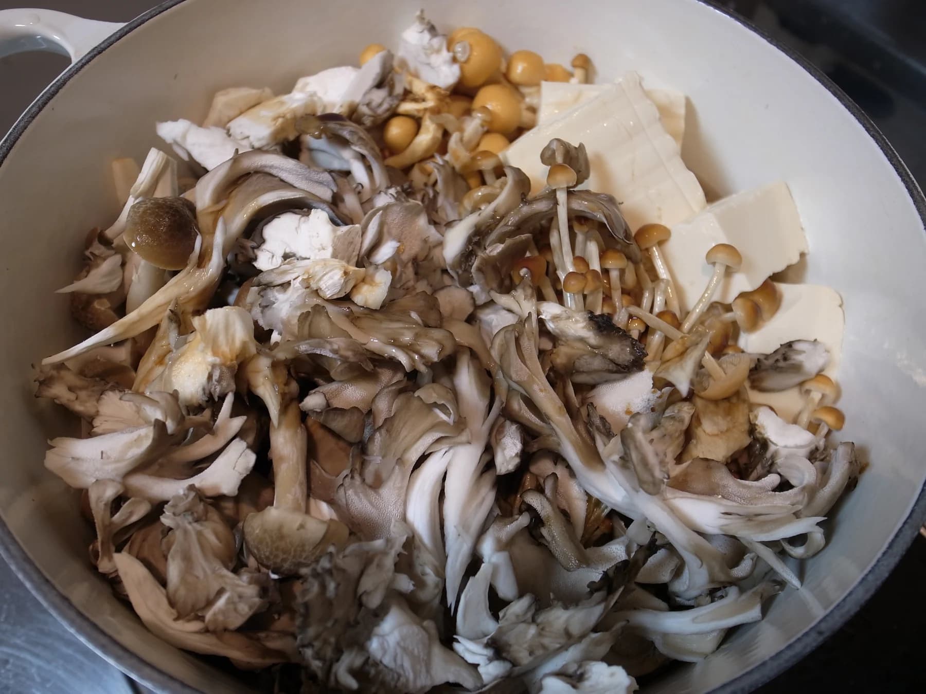 Fresh mushrooms and tofu arranged in a cooking pot