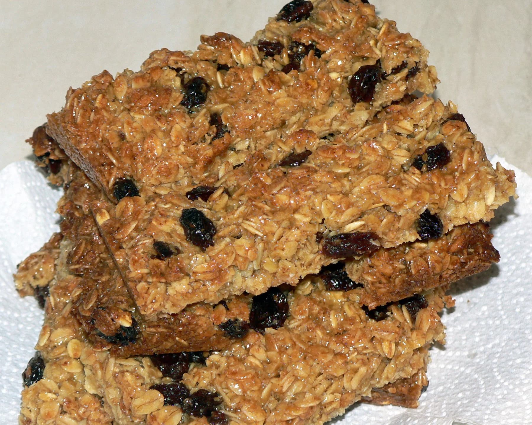 Baked oat and raisin squares stacked on a napkin