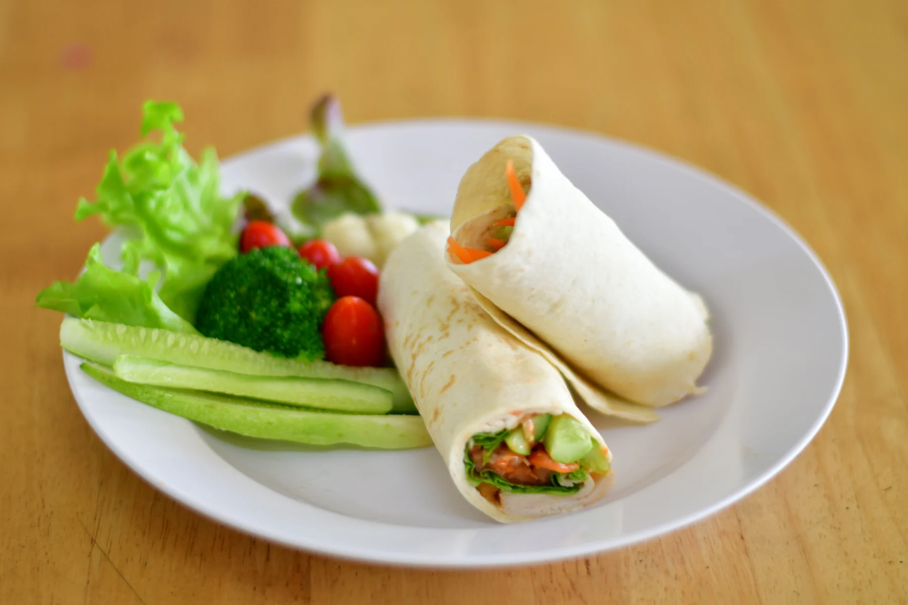 Vegetable wraps with cucumber, broccoli and lettuce on a white plate